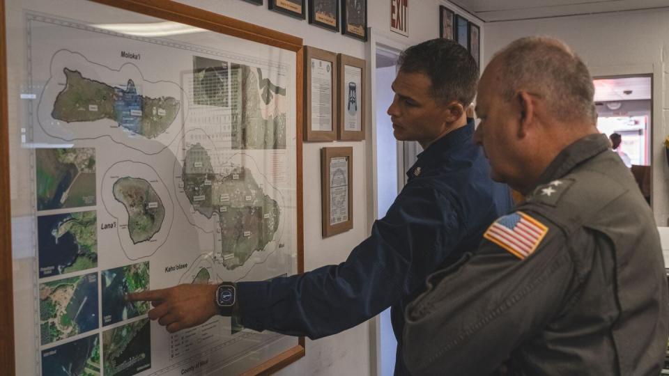 Petty Officer 1st Class Matthew Casper, left, advises Rear Adm. Michael Day about rescue operations during the 2023 wildfires in Maui. (Petty Officer 3rd Class David Graham/Coast Guard)