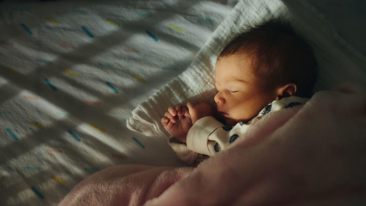 Close-up of a newborn baby girl peacefully sleeping in the crib.