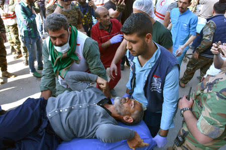 Men carry a stretcher of one of the evacuees from the two rebel-besieged Shi'ite villages of al-Foua and Kefraya, upon his arrival to government-controlled Aleppo, in this handout picture provided by SANA on April 19, 2017, Syria. SANA/Handout via REUTERS