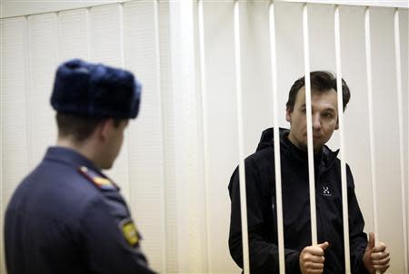 Greenpeace activist Tomasz Dziemianczuk of Poland, one of 30 people arrested over a Greenpeace protest at the Prirazlomnaya oil rig, looks out from a defendants' cage during a court session in St. Petersburg, November 19, 2013. REUTERS/Maxim Zmeyev