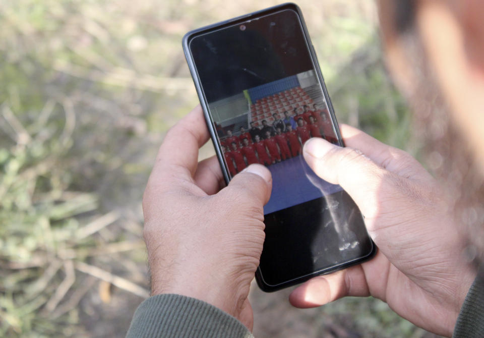 Ibrahim Rasool, Afghan refugee, formerly a FIFA-licensed futsal referee looks at photos on his phone at a makeshift camp housing migrants, in Velika Kladusa, Bosnia, Saturday, Nov. 13, 2021. Ibrahim Rasool loved his job as a futsal referee because of sportsmanship and fair play. But the 33-year-old man from Afghanistan says there is nothing fair about the way the European Union treats people seeking refuge from violence and war. (AP Photo/Edvin Zulic)