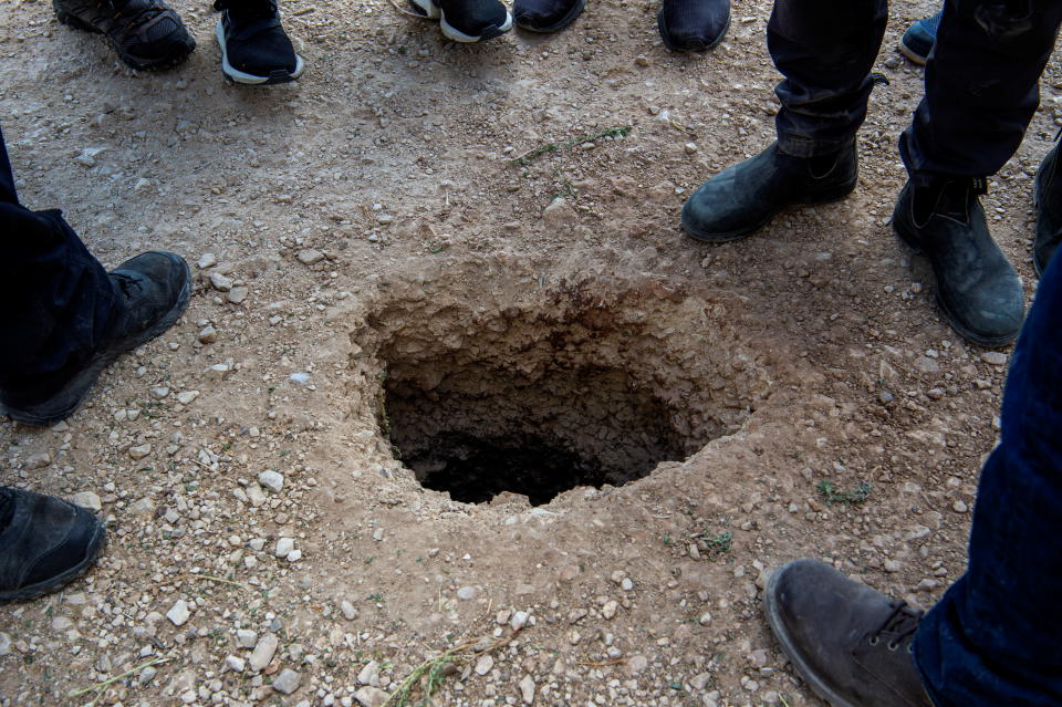 People stand by a hole in the ground outside the walls of Gilboa prison after six Palestinian militants broke out of it in north Israel September 6, 2021. REUTERS/ Gil Eliyahu