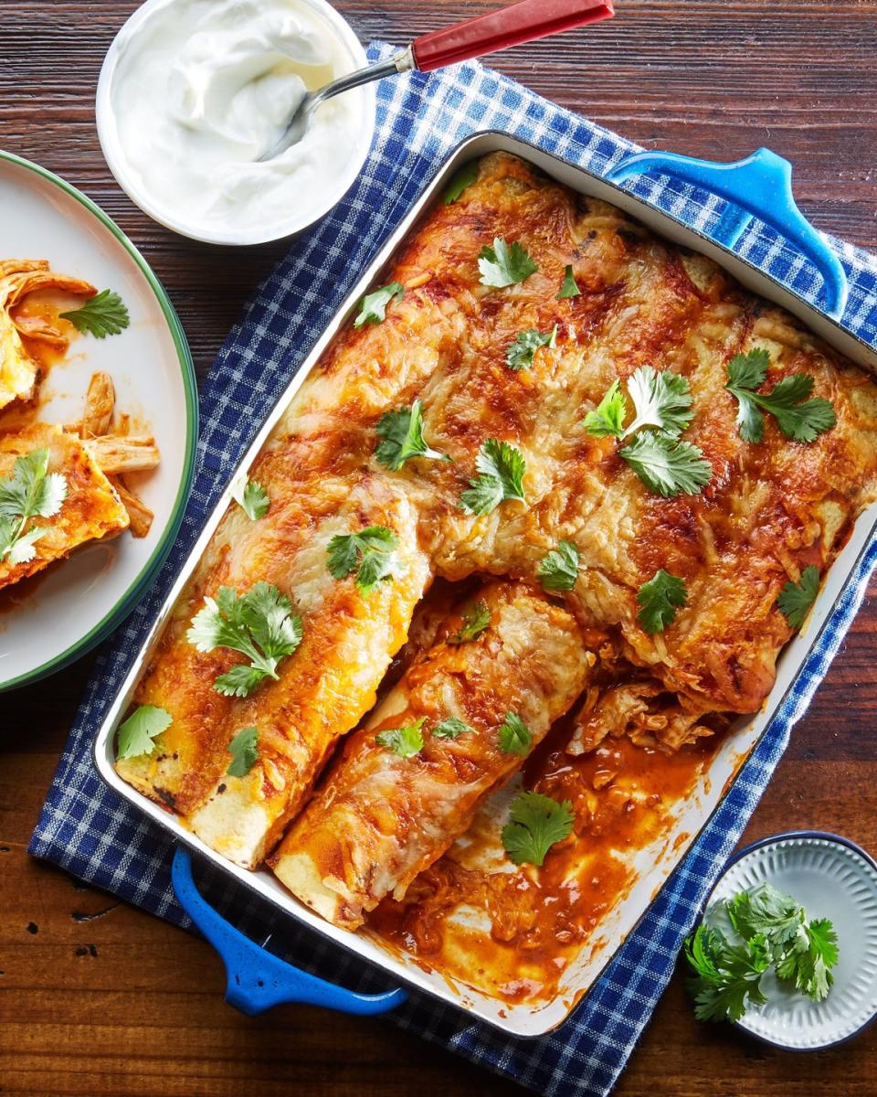 weeknight tex mex chicken enchiladas in a white rectangle casserole dish with blue handles and topped with fresh cilantro