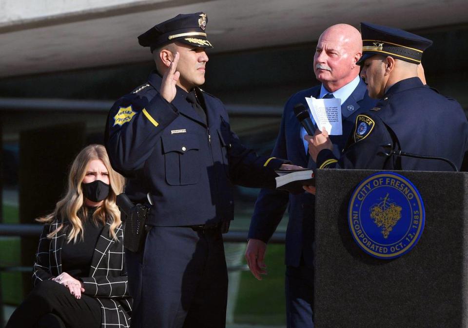 Paco Balderrama, second from left, raises his hand during the swearing-in ceremony delivered by his brother Beto Balderrama, far right, with former police chief Jerry Dyer in the center background and Kyla Balderrrama to the far left, in front of Fresno City Hall Monday morning, Jan. 11, 2021 in Fresno.