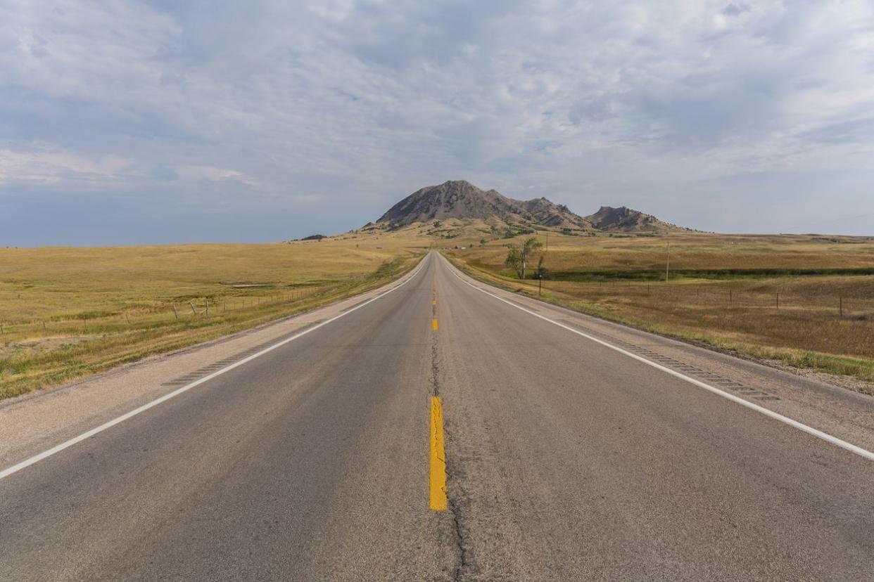 A highway leading to a butte.