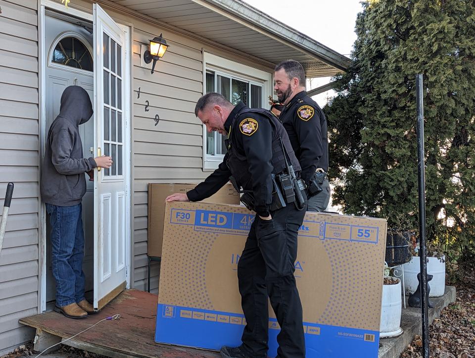 Sheriff Chris Hilton, in back, and Deputy John Johanssen deliver a television to a boy as part of the department’s First Annual Christmas Giveaway Spectacular. More than a dozen members of the Sandusky County Sheriff's Office took part delivering gifts to 75 families.