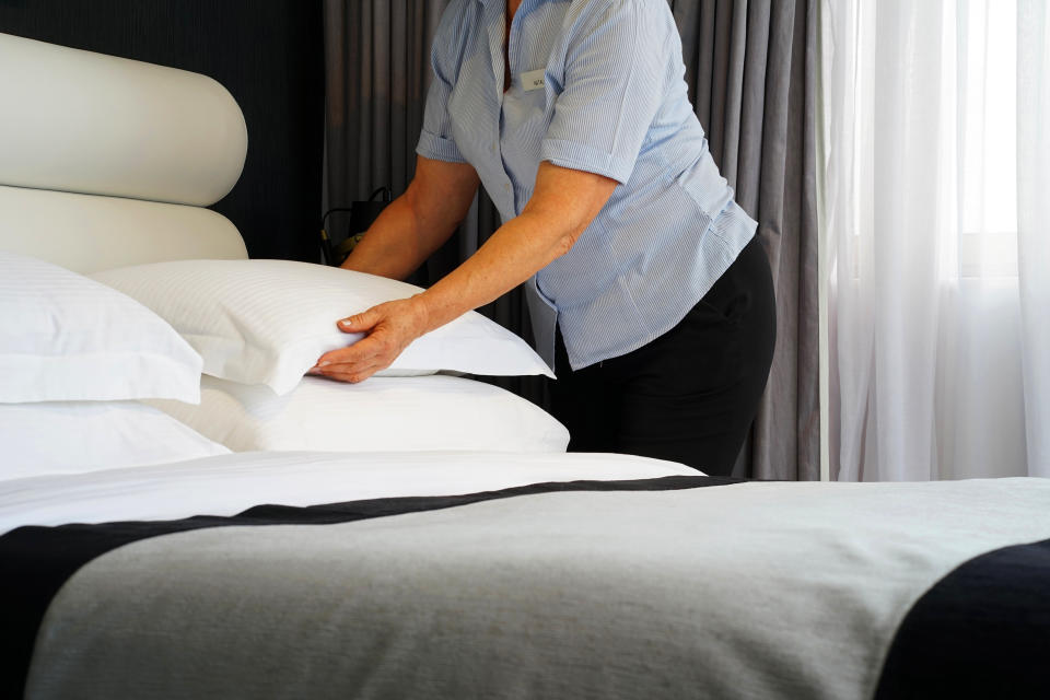 Maid making bed in hotel room