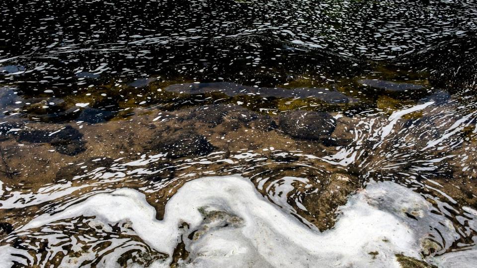 PFAS foam gathers at the the Van Etten Creek dam in Oscoda Township, Michigan, near Wurtsmith Air Force Base on June 7, 2018. (Jake May/The Flint Journal via AP)