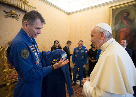 Pope Francis receives an astronaut suit from Italian astronaut Paolo Nespoli during a private meeting with crew members of the ISS 53 space mission at the Vatican June 8, 2018. Vatican Media/Handout via REUTERS