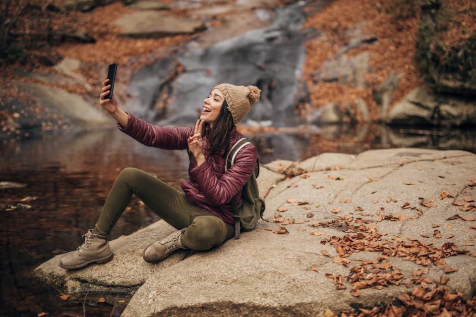 A content creator filming a video with a smartphone in a forest.