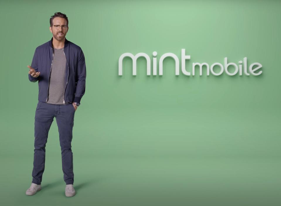 Ryan Reynolds standing in front of a green screen that says Mint Mobile