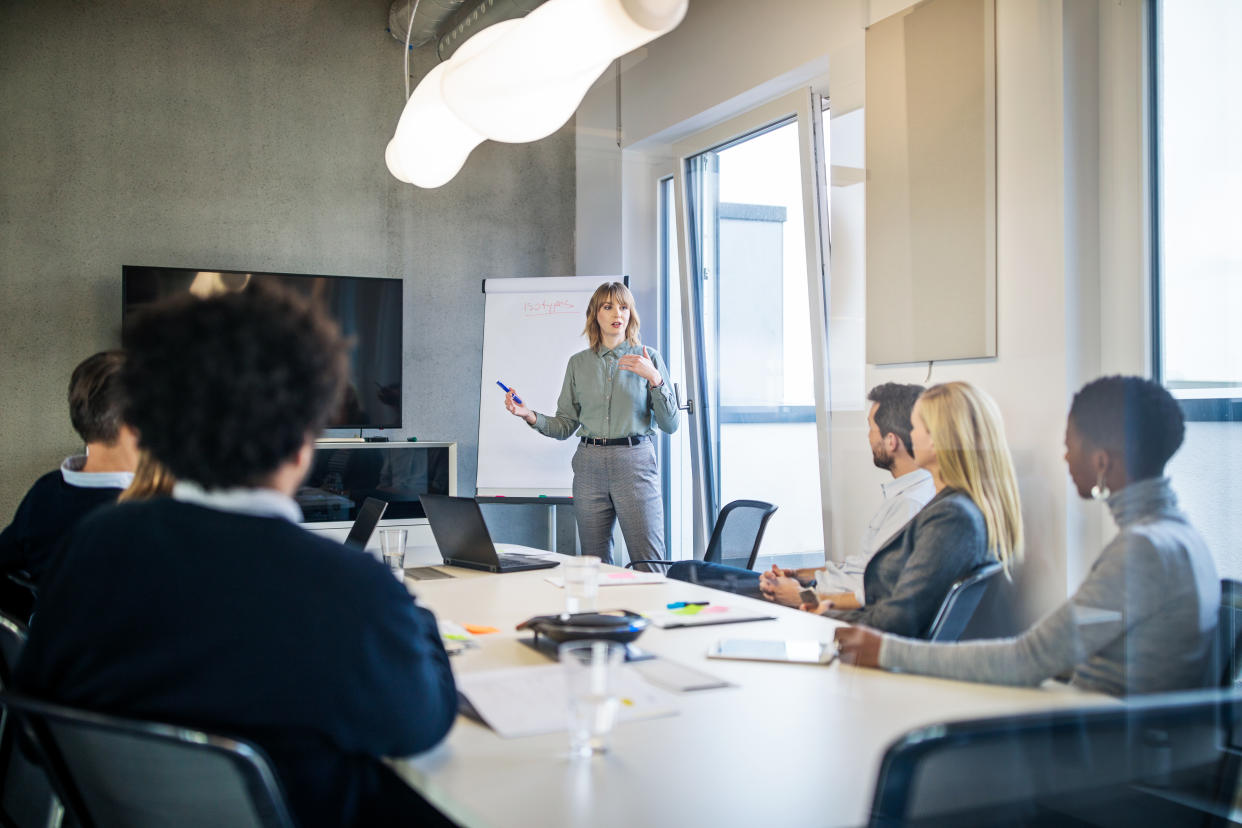 Businesswoman addressing a meeting around board table. Group of business people having board meeting in modern office.