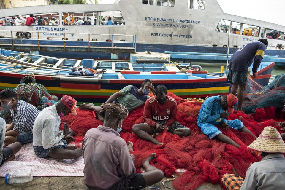 Fishermen wearing masks as a precaution against the coronavirus repair their nets in Kochi, Kerala state, India, Monday, Aug. 23, 2021. (AP Photo/R S Iyer)