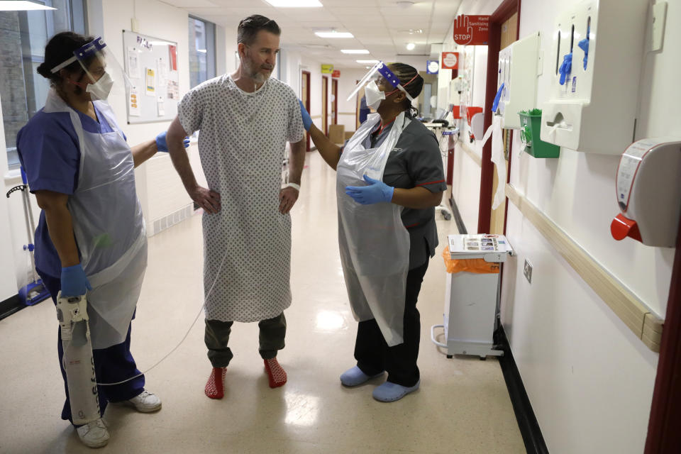 Felicia Kwaku, Associate Director of Nursing, right, and Anna Castellano, Matron, left, help recovering COVID-19 Justin Fleming walk again, on the Cotton ward at King's College Hospital in London, Wednesday, Jan. 27, 2021. Fleming is one of more than 37,000 coronavirus patients being treated now in Britain's hospitals, almost double the number of the spring surge. King's College Hospital, which sits in a diverse, densely populated area of south London, had almost 800 COVID-19 patients earlier this winter. (AP Photo/Kirsty Wigglesworth, Pool)