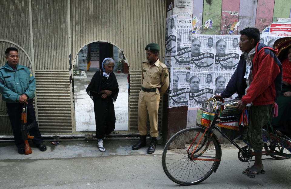 Bangladeshi security officials stand guard as a woman leaves a polling station after casting her vote in Dhaka, Bangladesh, Sunday, Jan. 5, 2014. Voting has started in Bangladesh for general elections Sunday that threaten to deepen the crisis in the South Asian nation. The opposition and its allies are boycotting the vote, a move that undermines the legitimacy of the election and makes it unlikely that the polls will stem a wave of political violence that killed at least 275 people in 2013. (AP Photo/ Rajesh Kumar Singh)