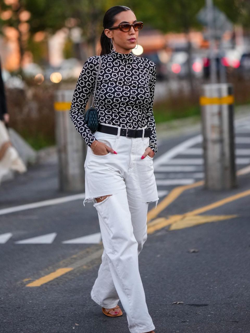 A Fashion Week guest teams white jeans with a monochrome print top 