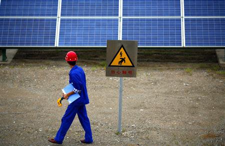 A worker inspects solar panels at a solar farm in Dunhuang, 950km (590 miles) northwest of Lanzhou, Gansu Province September 16, 2013. REUTERS/Carlos Barria