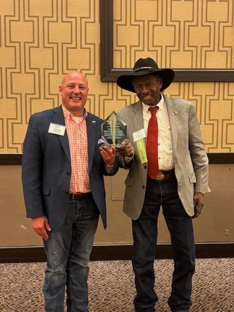 OCM President Taylor Haynes presents The John Helmuth Award to Marty Irby in May of 2024