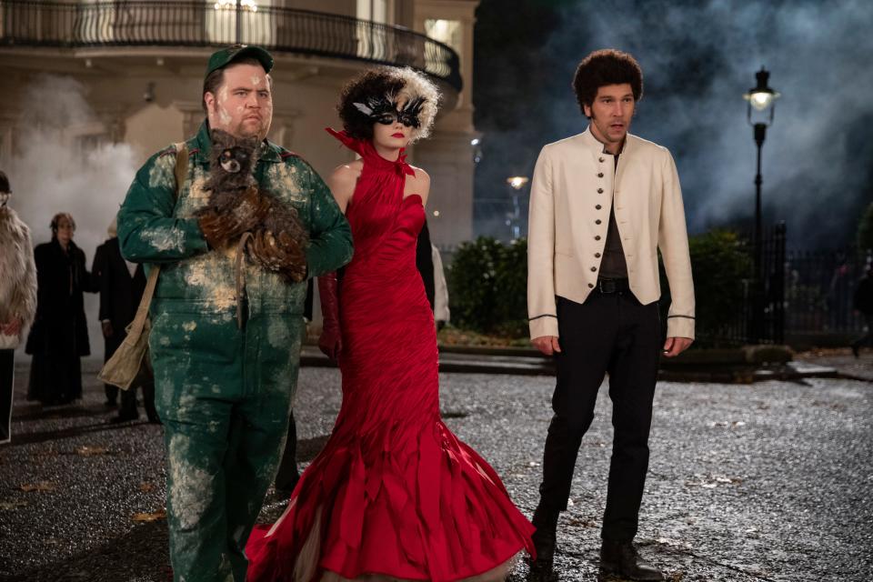 Cruella (Emma Stone, center) and her thieving cohorts Horace (Paul Walter Hauser) and Jasper (Joel Fry) are a makeshift family in "Cruella."