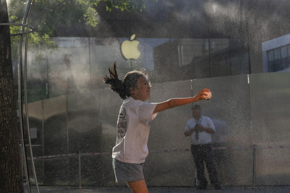 A girl plays near a mist machine to cool off from the summer heat in Beijing, Saturday, June 15, 2024. (AP Photo/Ng Han Guan)