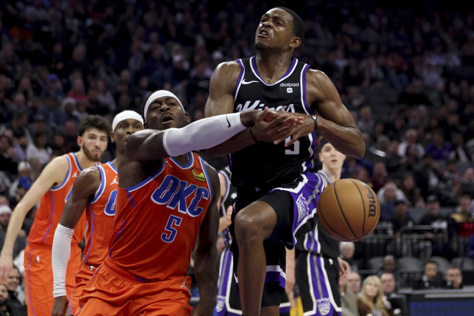 Sacramento Kings guard De'Aaron Fox, front right, is defended by Oklahoma City Thunder guard Luguentz Dort, front left, during the first half of an NBA basketball game in Sacramento, Calif, Thursday, Dec. 14, 2023. (AP Photo/Jed Jacobsohn)