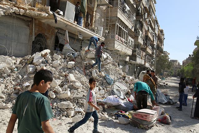 People remove belongings from a damaged site after an air strike Sunday in the rebel-held besieged al-Qaterji neighborhood of Aleppo.  Photo: Reuters/Abdalrhman Ismail