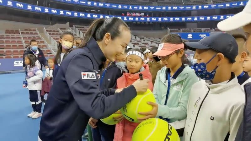 Chinese tennis player Peng Shuai signs large-sized tennis balls at the opening ceremony of Fila Kids Junior Tennis Challenger Final in Beijing