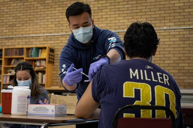 Hector Aparicio, 34, gets his first dose of the Moderna COVID-19 vaccine in the common room of his apartment building in Toronto’s Jane and Wilson neighbourhood on Apr. 13, 2021. (Evan Mitsui/CBC - image credit)