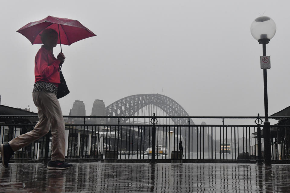 A pedestrian walks past the Sydney Harbour Bridge during wet weather in Sydney, Wednesday, November 10, 2021.