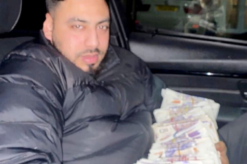 Mohammed Asim in a car posing with thousands of pounds in cash