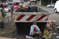 Fabian Ramirez, 11, scavenges a trash container for vegetables with his family that were discarded at the "Mercado de Abasto," a market for vendors, during the fourth week of a quarantine to help contain the spread of the new coronavirus in Asuncion, Paraguay, Thursday, April 2, 2020. COVID-19 causes mild or moderate symptoms for most people, but for some, especially older adults and people with existing health problems, it can cause more severe illness or death. (AP Photo/Jorge Saenz)