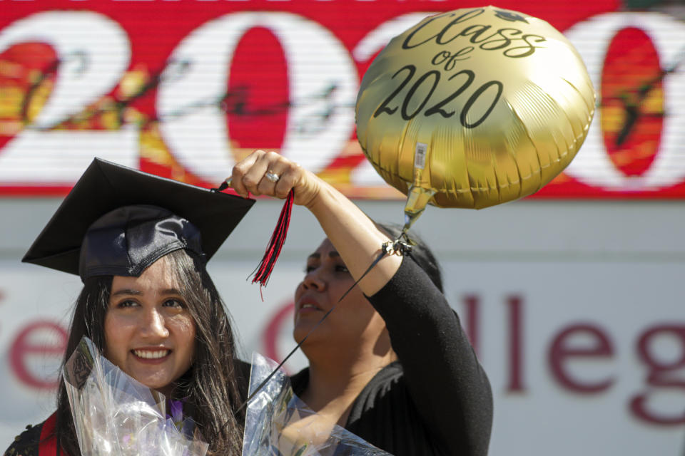 RANCHO CUCAMONGA, CA - MAY 20: Melissa Gomes, right, fixes the tassel as new graduate Sarah Anggraini gets ready for a photo at the marquee of Chaffey Colleges that held a drive through graduation on Wednesday, May 20, 2020 in Rancho Cucamonga, CA. (Irfan Khan / Los Angeles Times via Getty Images)