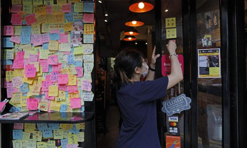 An employee removes stickers and posters with messages in support of the pro-democracy movement at a restaurant in Hong Kong.