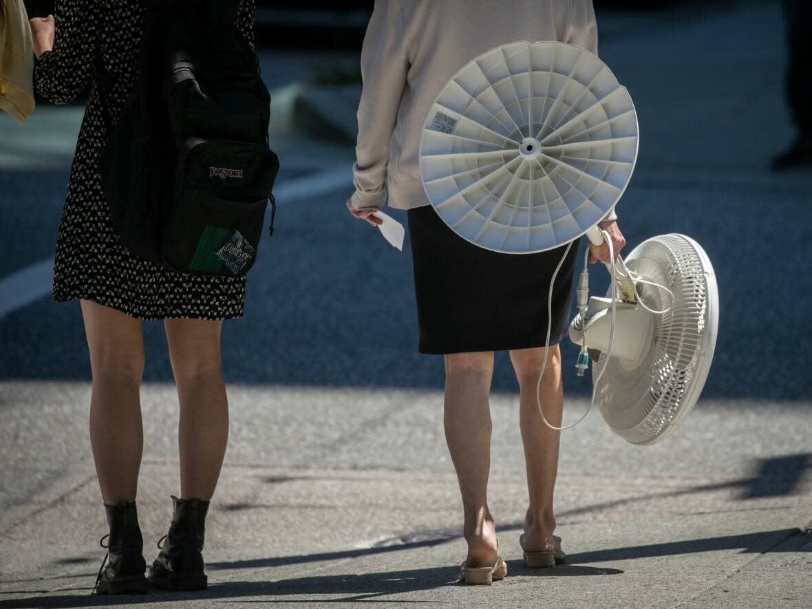 A woman walks with a fan during a period of hot weather in Vancouver, B.C. in July 2022. The city recorded its second warmest October since 1896, about 1.7 C warmer than average. (Ben Nelms/CBC - image credit)