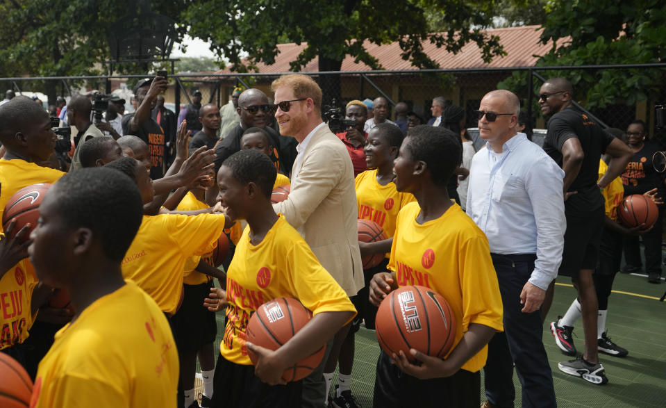 Prince Harry, center, shake hands with children during the Giant of Africa Foundation at the Dream Big Basketball clinic in Lagos Nigeria, Sunday, May 12, 2024. Prince Harry and his wife Meghan are in Nigeria to champion the Invictus Games, which Prince Harry founded to aid the rehabilitation of wounded and sick servicemembers and veterans. (AP Photo/Sunday Alamba)