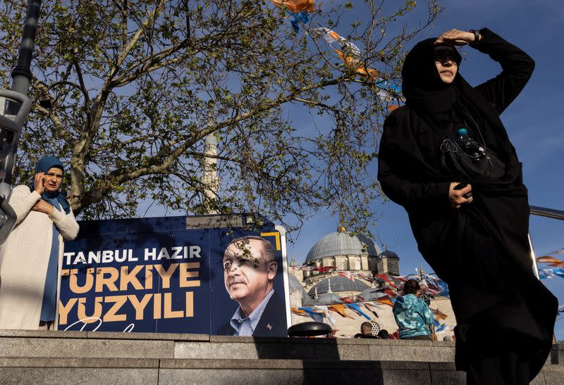 People walk past a campaign vehicle carrying a picture of Turkish President Tayyip Erdogan in Istanbul