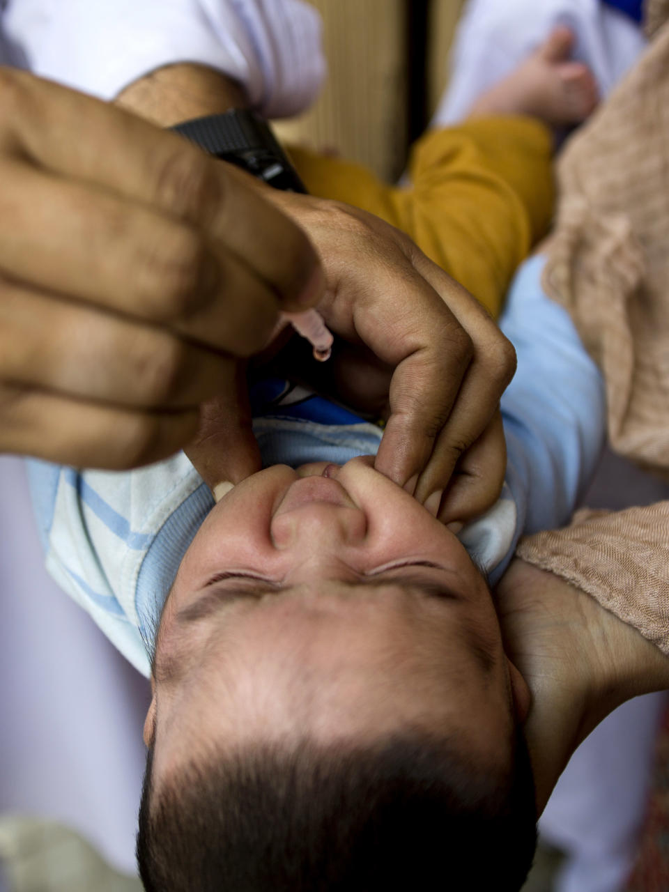 A Pakistani health worker gives a polio vaccine to a child in Rawalpindi, Pakistan, Tuesday, May 6, 2014. Pakistan’s health minister says the country is taking extra ordinary measures to meet the new situation it is going to face after polio travel restrictions. (AP Photo/B.K. Bangash)