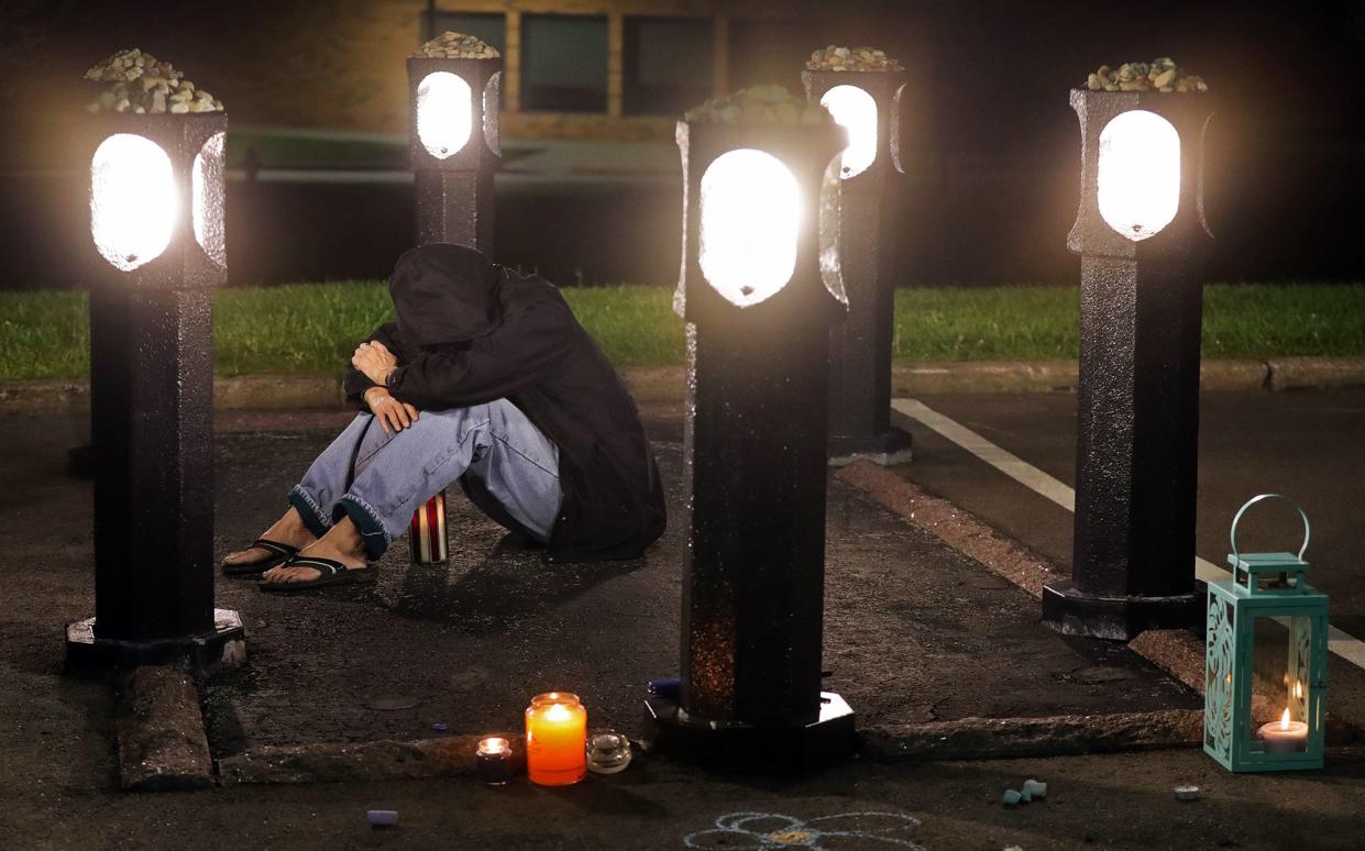 A hooded woman mourns at the May 4 memorial for William Schroeder during a candlelight vigil at Kent State, May 4, 2020.