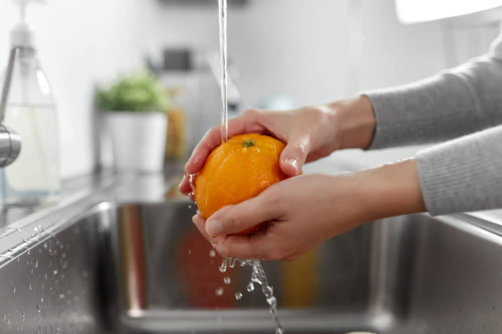 washing orange in sink