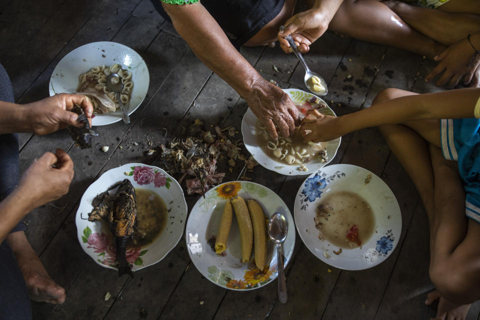 Barbaran family members eat lunch prior to the burial service of their relative Jose Barbaran who is believed to have died from complications related to the new coronavirus, in Palestina, in Peru's Ucayali region, Wednesday, Sept. 30, 2020. As Peru grapples with one the world's worst virus outbreaks, another epidemic is starting to raise alarm: Dengue. (AP Photo/Rodrigo Abd)