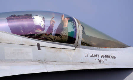 A pilot for a U.S. Navy F18 fighter jet gives hand signals to ground crew before taking off on aircraft carrier USS Carl Vinson. REUTERS/Erik De Castro