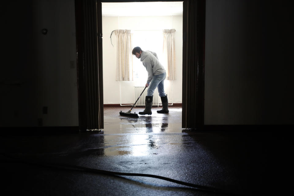 Brandon Lynch, of Beattyville, Ky., works to clear water inside of Newnam Funeral Home after heavy rains caused the Kentucky River to flood most of downtown Beattyville, Ky., Tuesday, March 2, 2021. (Alex Slitz/Lexington Herald-Leader via AP)