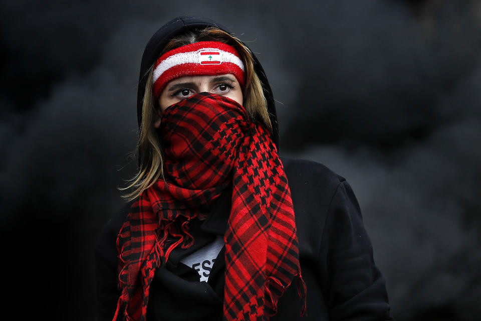 FILE- A protester covers her face with a scarf as she blocks a main highway during a protest against the increase in prices of consumer goods and the crash of the local currency, in the town of Zouk Mosbeh, north of Beirut, Lebanon, Monday, March 8, 2021. Lebanon and Sri Lanka may be a world apart, but they share a history of political turmoil and violence that led to the collapse of once-prosperous economies bedeviled by corruption, patronage, nepotism and incompetence. (AP Photo/Hussein Malla, File)