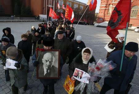 Communist supporters hold flags and portraits of Soviet State founder Vladimir Lenin during a wreath laying ceremony at the Lenin's mausoleum on Moscow's Red Square January 21, 2015. REUTERS/Sergei Karpukhin