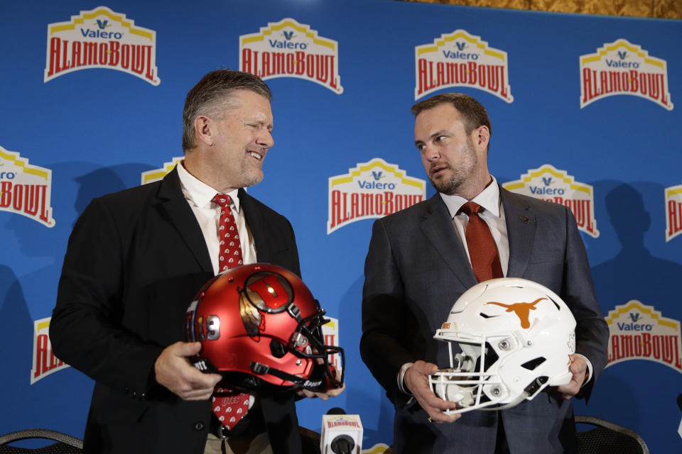 Utah head coach Kyle Whittingham, left, and Texas head coach Tom Herman, right, pose for photos during a news conference for the Alamo Bowl NCAA college football game, Thursday, Dec. 12, 2019, in San Antonio. (AP Photo/Eric Gay)