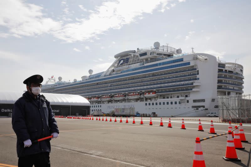 A man wearing a mask stands guard at the port next to the cruise ship Diamond Princess at Daikoku Pier Cruise Terminal in Yokohama, south of Tokyo
