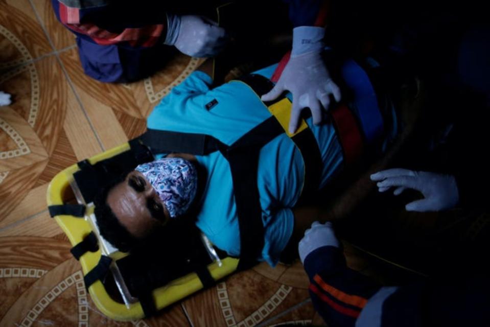 Los sanitarios preparan a Valder da Silva, de 51 años, para llevárselo en un barco ambulancia al hospital tras dar positivo por coronavirus. (Foto: Uesley Marcelino / Reuters).