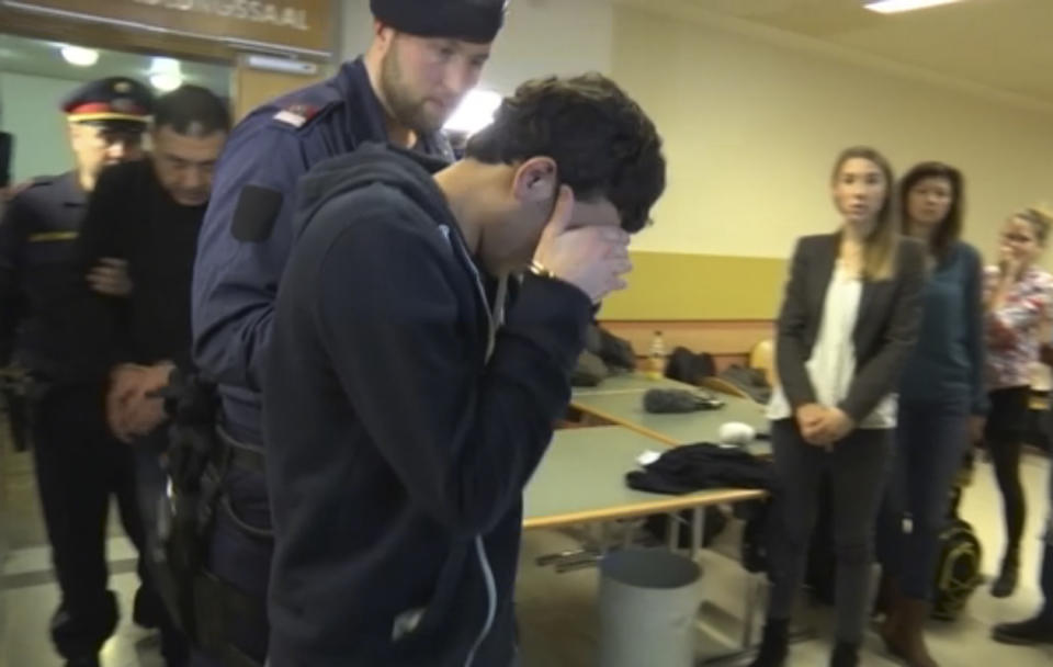 A defendant covers his face as he is lead out of the court room after his trial on gang-raping a German tourist in Vienna, Austria, Thursday, March 2, 2017. Eight Iraqi nationals have been given jail sentences of between nine and 13 years. (AP Photo/Philipp Jenne)