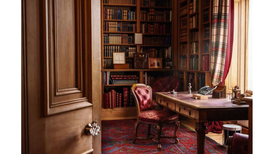 A library with bookshelves and a desk with a red chair