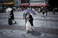 <p>A woman holds an umbrella as she walks along a street in Tokyo on July 23, 2018, as Japan suffers from a heatwave. (Photo: Martin Bureau/AFP/Getty Images) </p>